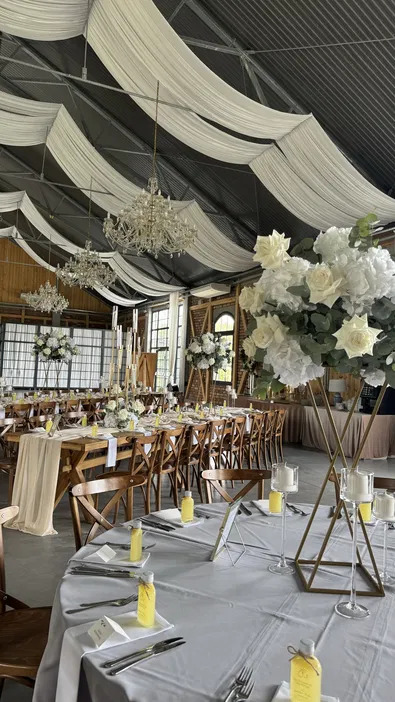 Elegancka sala weselna z dekoracjami kwiatowymi, stołami bankietowymi i eleganckimi żyrandolami, przygotowana na uroczystość weselną.