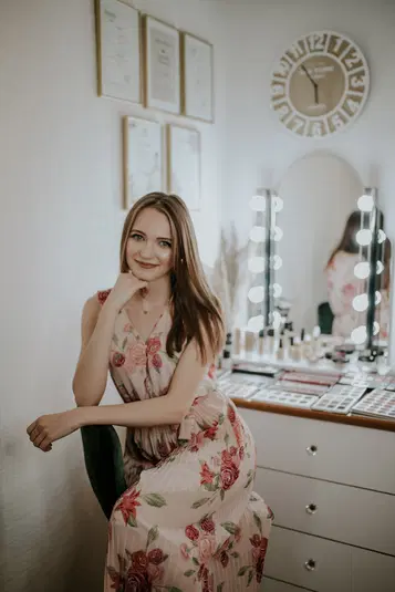  Nie wiem, kto jest na zdjęciu, ale oto odpowiedni alt:

Elegancka kobieta w kwiecistej sukni siedząca przy toaletce z lustrami i oświetleniem, wnętrze salonu kosmetycznego. 