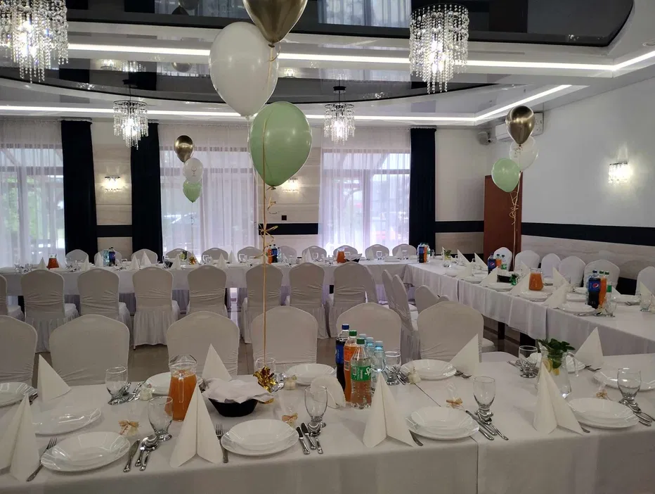 Sala bankietowa na przyjęcie, dekoracje stołu, balony, białe krzesła, zastawa stołowa, elegancka aranżacja wnętrza, przygotowanie na wesele lub uroczystość.