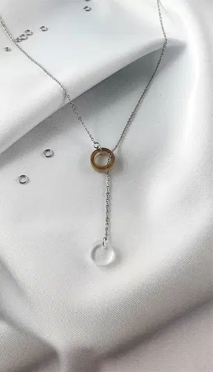  Naszyjnik z delikatnym łańcuszkiem i dwoma kółkami, zdjęcie na białej tkaninie. Idealny dodatek do eleganckich stylizacji. 