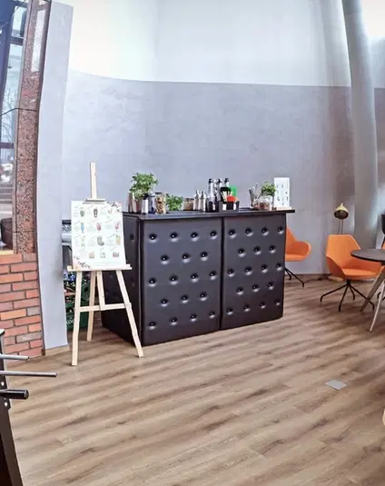 Nowoczesne wnętrze z czarnym barem, dekoracyjnymi roślinami i pomarańczowymi krzesłami na drewnianej podłodze. 