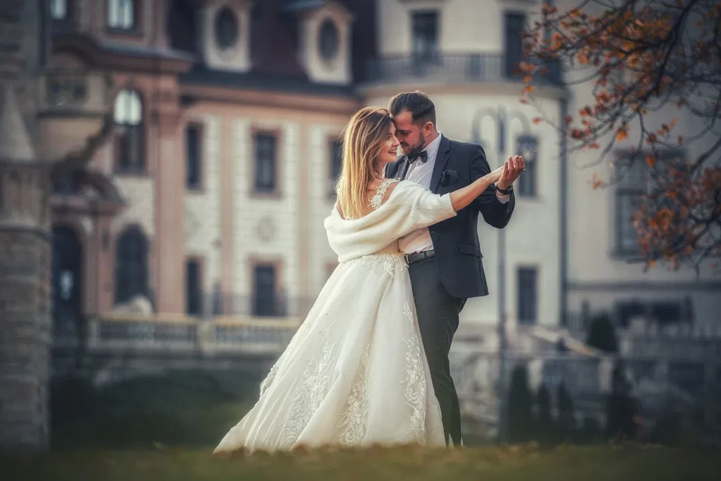 Para młoda tańcząca przed zamkiem, ślubna sesja zdjęciowa na tle zabytkowej architektury, romantyczny plener, elegancka panna młoda w białej sukni.