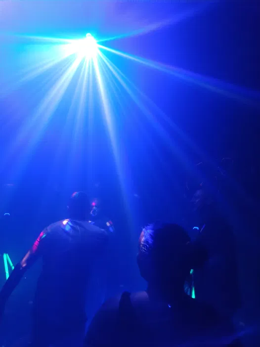 Osoby tańczące w dyskotece z niebieskim światłem laserowym