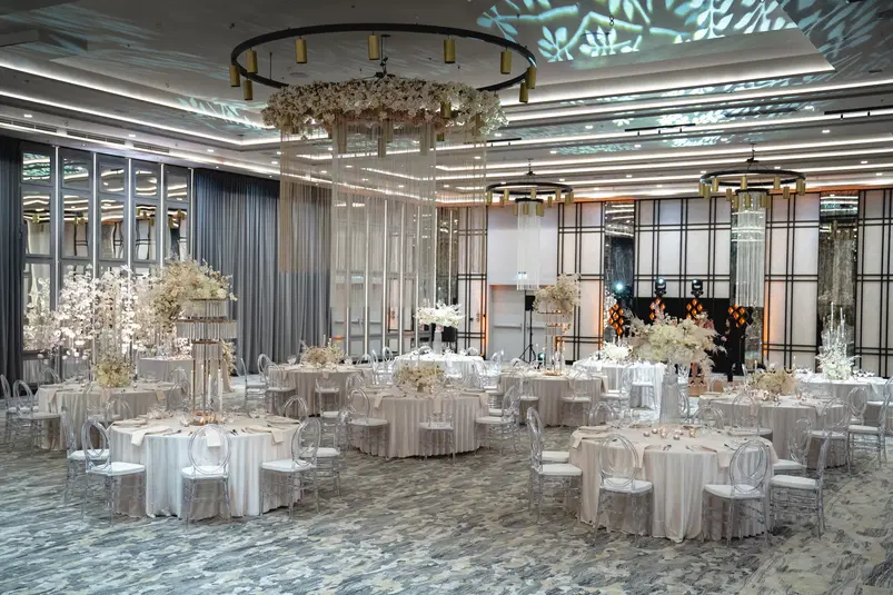  Elegancka sala weselna z okrągłymi stołami, białymi obrusami i kwiatowymi dekoracjami, nowoczesny wystrój wnętrza, luksusowa aranżacja, przygotowanie na przyjęcie weselne. 