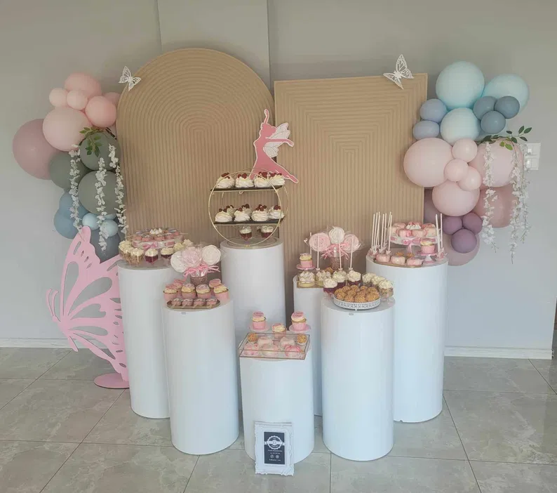 Dekoracja na przyjęcie urodzinowe z motywem baleriny, różowe balony, białe kolumny z muffinkami i trzypoziomowy stojak z cupcakeami, akcenty w kształcie motyla.