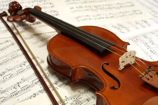 Skrzypce leżące na nutach, klasyczny instrument muzyczny, muzyka klasyczna, struny i smyczek, eleganckie drewniane wykończenie, koncert muzyczny. 