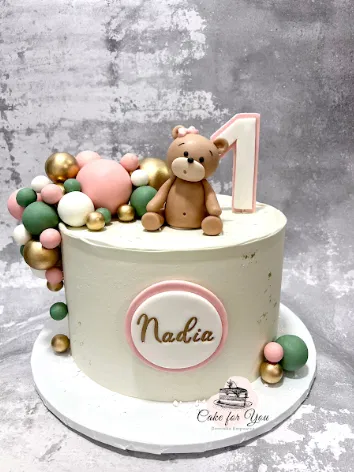 Tort urodzinowy z misiem i kulkami w pastelowych kolorach, dekoracja w formie cyferki 1, imię Nadia, elegancki design, idealny na pierwsze urodziny.