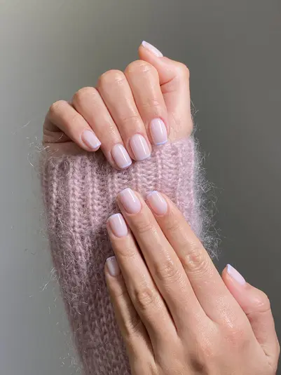  Elegancki manicure z naturalnymi paznokciami w delikatnym odcieniu różu na tle różowego, wełnianego swetra. 