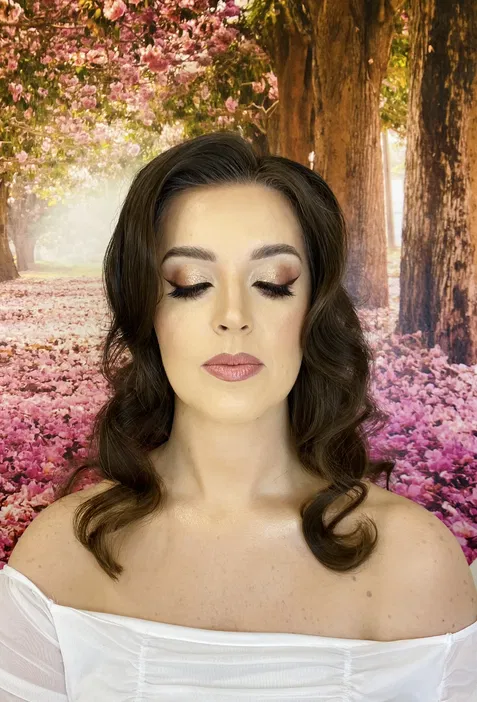 Glamour makeup na kobiecie z zamkniętymi oczami, z tłem kwitnących drzew i różowych kwiatów.