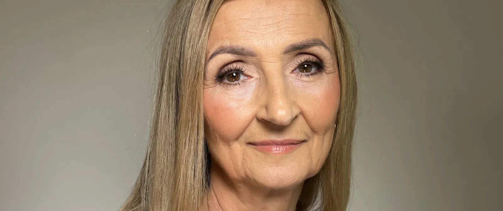 Nieznana kobieta o długich blond włosach, stonowane tło.