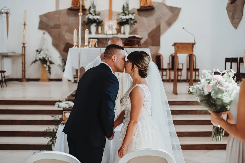  Para młoda w kościele podczas ceremonii ślubnej, moment pocałunku przed ołtarzem. 