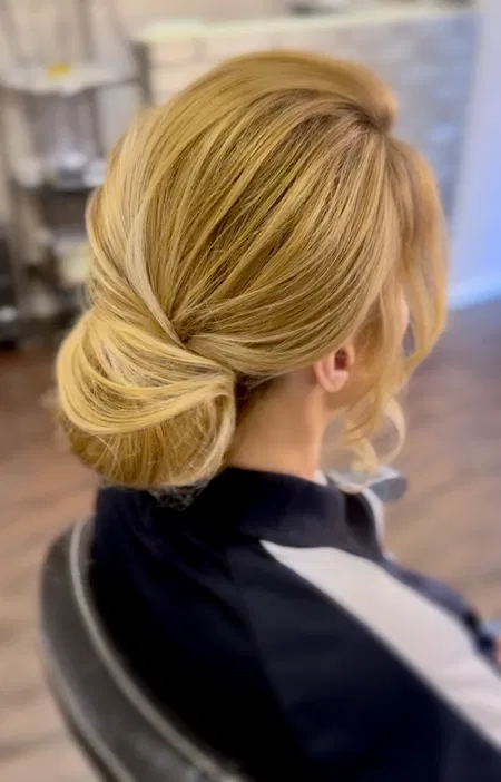 Upięcie włosów blond, elegancki niski kok, stylizacja ślubna, fryzura wieczorowa, salon fryzjerski.
