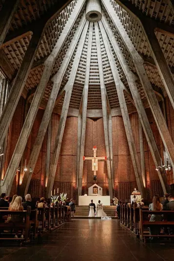  Wnętrze nowoczesnego kościoła z drewnianym sklepieniem, para młoda przed ołtarzem, sakralna architektura, ceremonia ślubna. 
