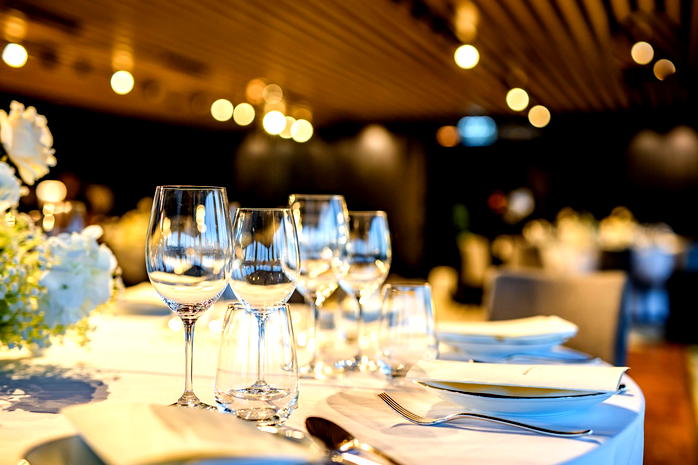  Elegancko nakryty stół w restauracji z kieliszkami do wina i talerzami na białym obrusie. 