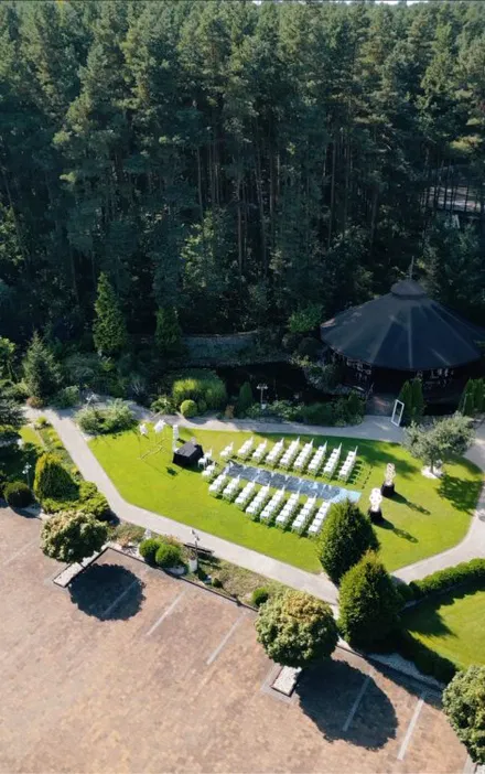 Plenerowe wesele w lesie, ustawienie krzeseł na trawie, elegancka ceremonia na świeżym powietrzu, otoczenie lasu i zieleni
