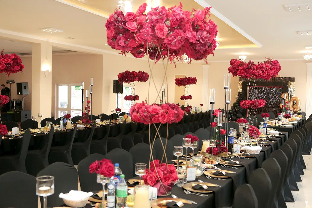 Elegancka sala bankietowa z czarnymi obrusami, dekoracjami z czerwonych kwiatów i numerem 30 w tle, idealna na uroczystość lub przyjęcie.