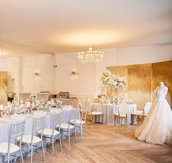  Elegancka sala weselna z białymi dekoracjami i stołami, manekin z suknią ślubną, luksusowe wnętrze, przygotowanie na eleganckie przyjęcie. 