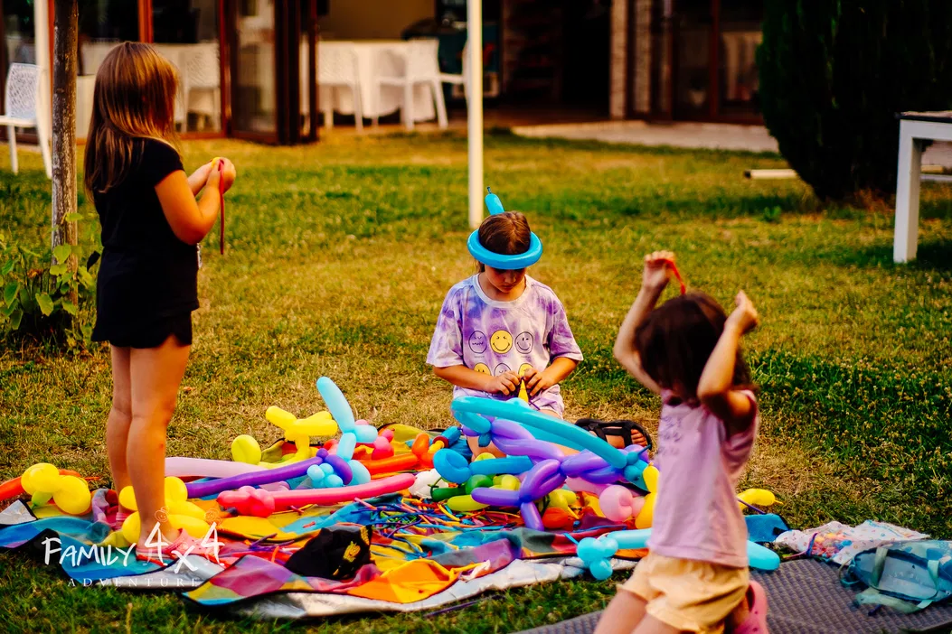 Dzieci bawiące się balonami na trawie w ogrodzie, kolorowe balony, zabawa na świeżym powietrzu, dzieciństwo, lato.