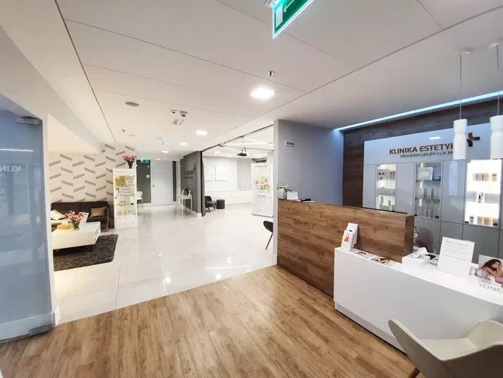  Wnętrze nowoczesnej kliniki estetycznej z recepcją, eleganckim wystrojem i produktami kosmetycznymi na półkach. 