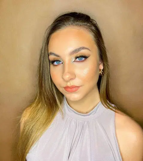 Nieznana kobieta o długich włosach, w makijażu glamour, na beżowym tle. 