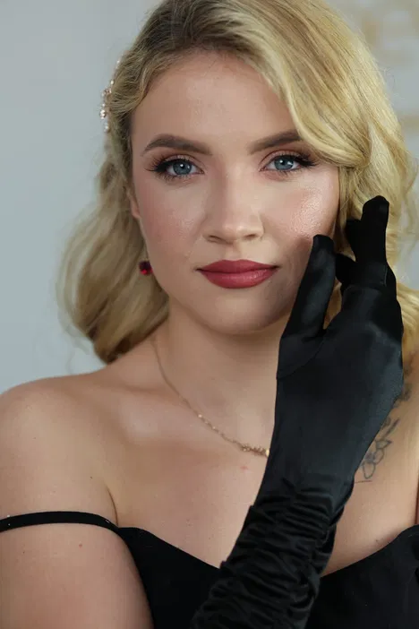 Kobieta w eleganckiej czarnej sukni z czarną rękawiczką, blond włosy, profesjonalny makijaż, zbliżenie na twarz, glamour.