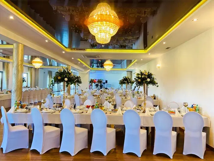  Elegancka sala weselna z luksusowym oświetleniem i piękną dekoracją stołów, idealna na przyjęcia i uroczystości. 