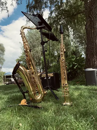  Instrumenty dęte blaszane na trawie obok wzmacniacza, Musica na świeżym powietrzu, saksofon barytonowy i altowy, letni koncert plenerowy. 