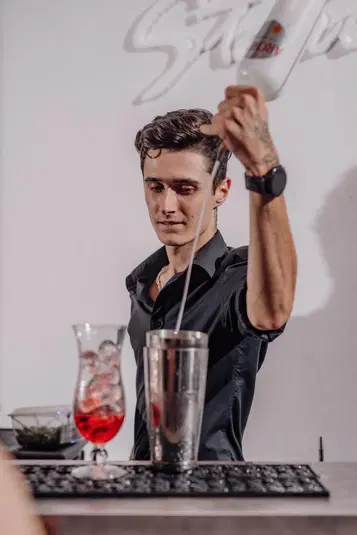  Bartender przygotowujący koktajl z lodem, profesjonalne miksowanie drinków w stylowym barze. 