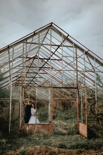  Para młoda w opuszczonej szklarni, rustykalna sesja ślubna, fotografia ślubna w plenerze, romantyczna sesja zdjęciowa, industrialne tło na zdjęciach ślubnych. 