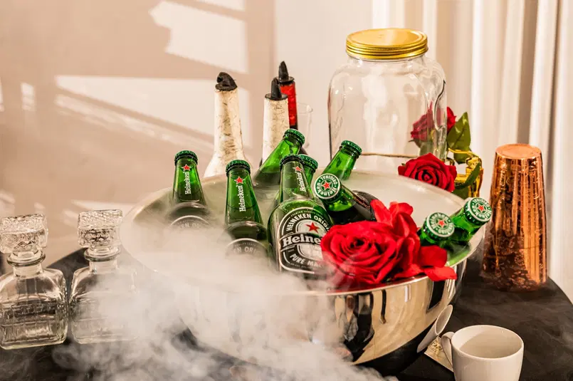  Alkoholowy stół z lodem, butelkami Heineken, czerwonymi różami i ozdobami na imprezie. 