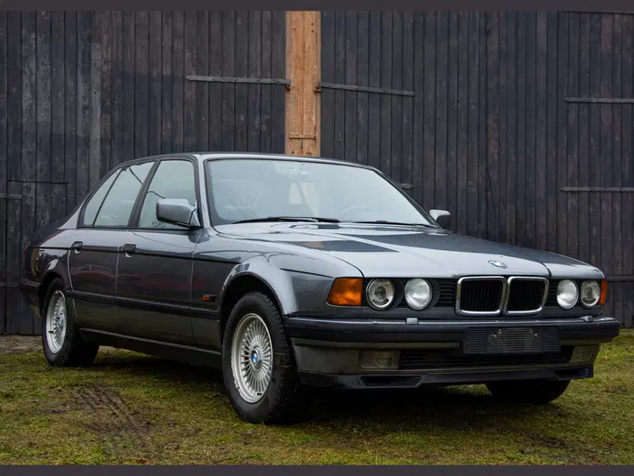  Klasyczny samochód sedan w stylu vintage stojący na tle drewnianej stodoły. 