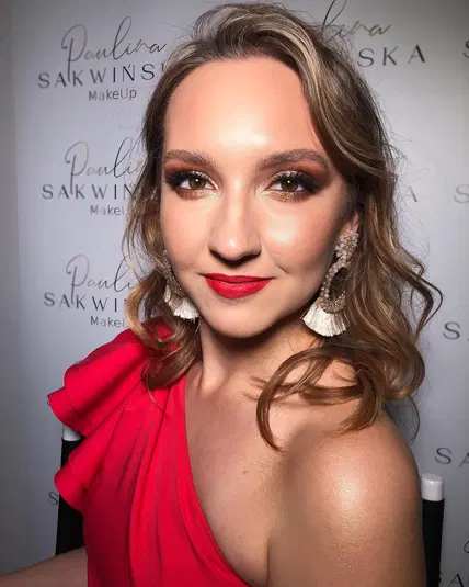  Eleganckie makijażowe stylizacje wieczorowe na imprezy - kobieta w czerwonej sukni z makijażem glamour i biżuterią, tło z logo Paulina Sakwińska MakeUp 